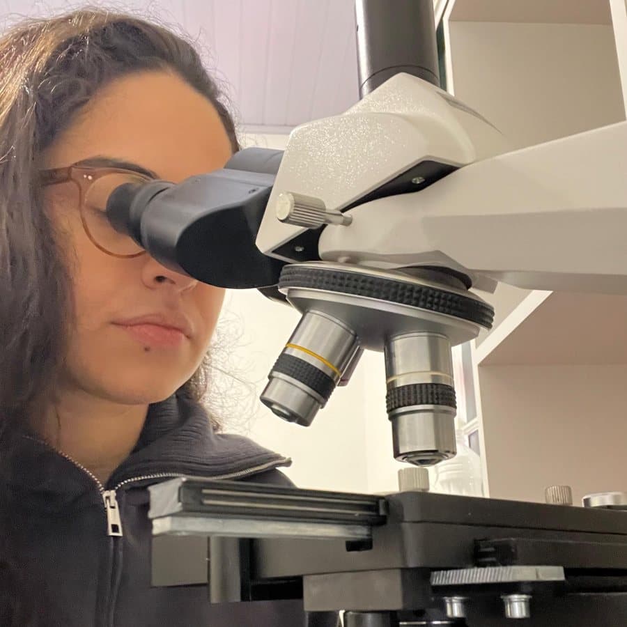 Dra. Gabriela Giannini analisando uma lâmina ao microscópio
