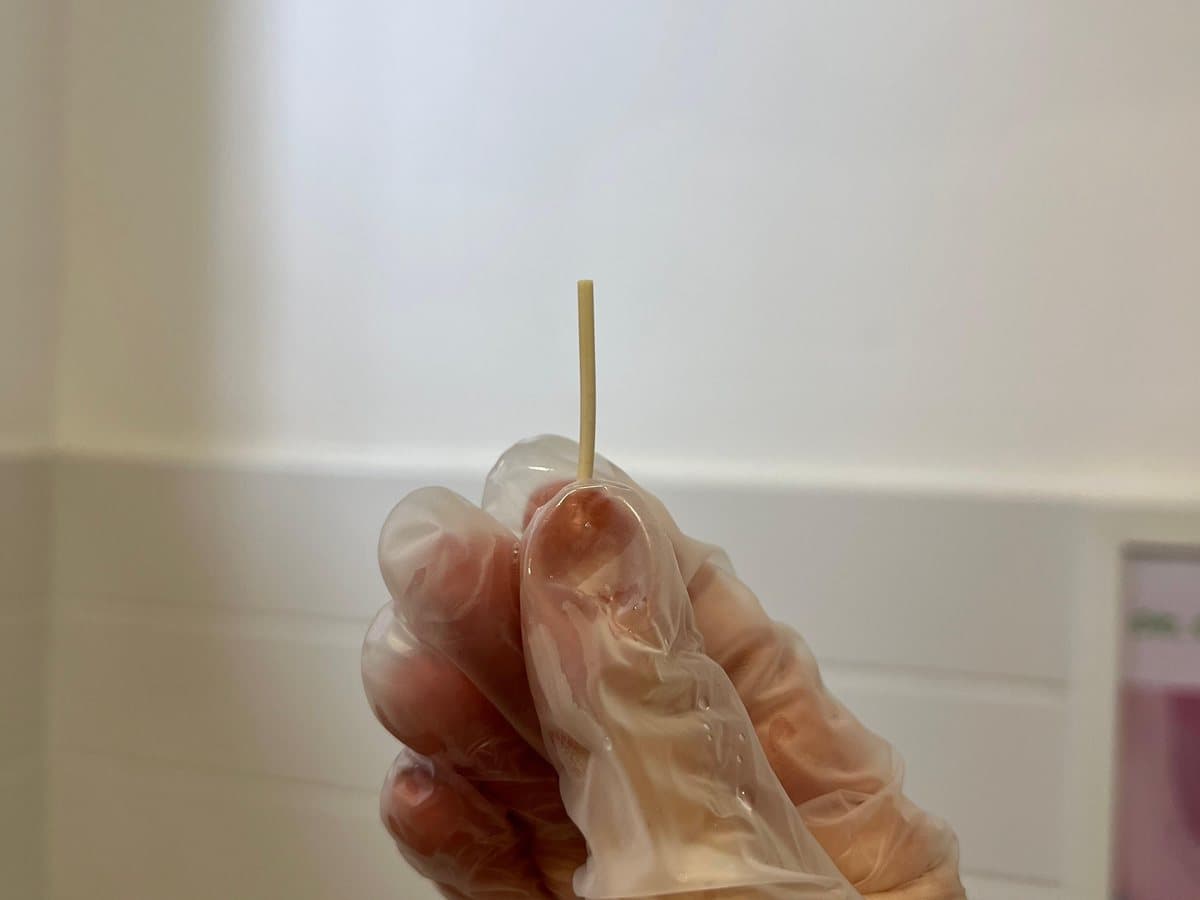 Implante contraceptivo segurado entre os dedos antes da colocação